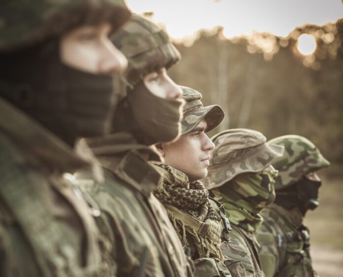 Heavily armed soldiers in battle dress uniform standing in a row outdoor